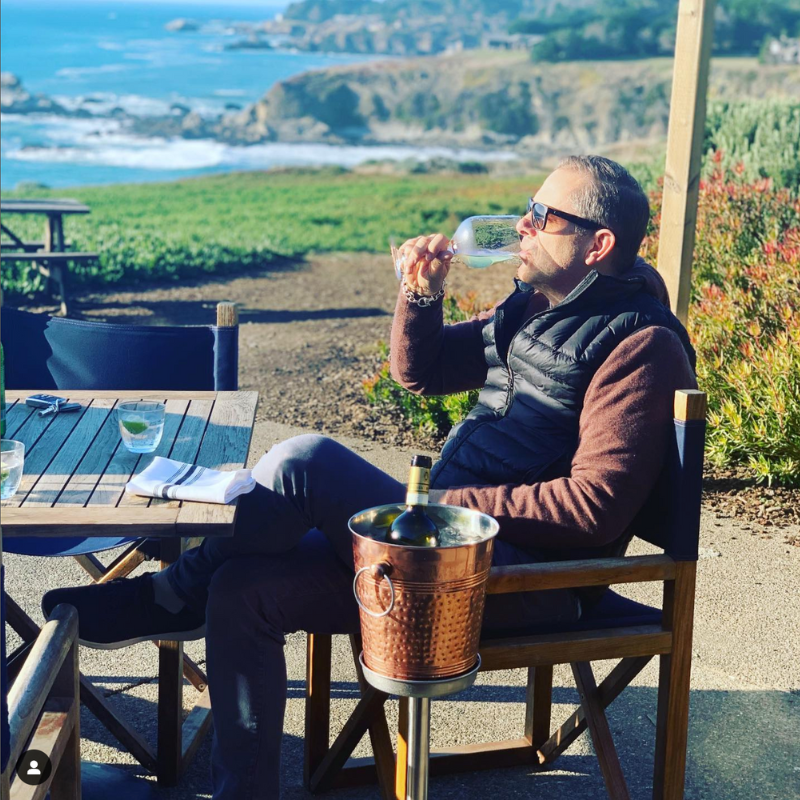 Arthur Goodrich, Managing Partner of Mayastoga luxury vacation rentals, enjoying a glass of exquisite wine on a scenic deck overlooking the ocean and cliffs at one of their stunning vacation homes in California