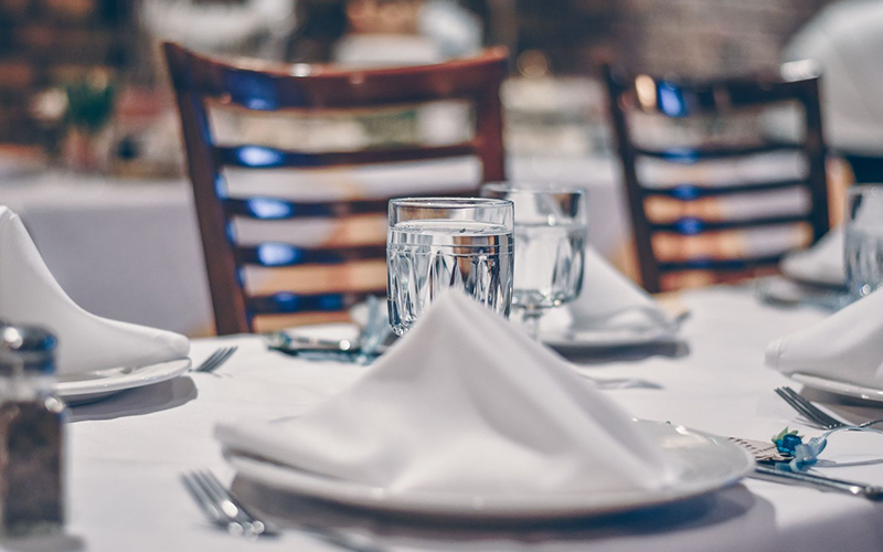 Closeup of a Michelin-starred restaurant table featuring white plates, cloth napkins, and glasses of water